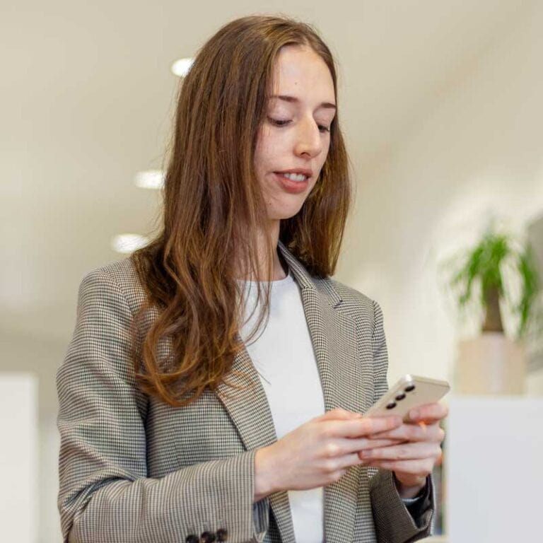 Mitarbeiterin Wibke unserer Social Media Agentur arbeitet am Smartphone für Marketing-Strategien